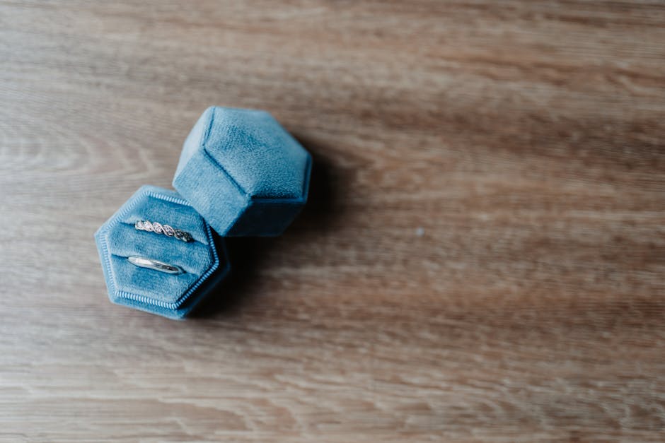 Close-up of rings in a blue velvet box on a wooden surface.