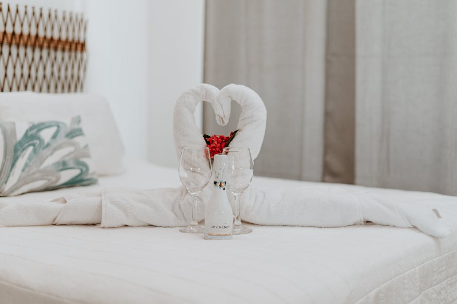 A luxurious hotel room with swan towel decoration and wine glasses on the bed.