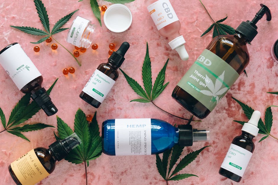 Flat lay of CBD products with cannabis leaves on pink fabric, perfect for wellness theme.