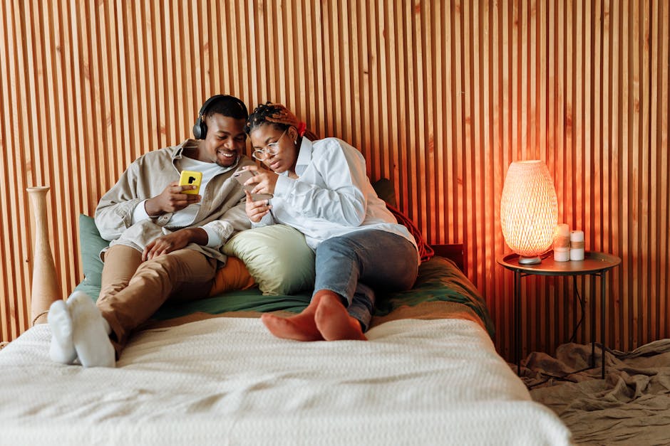 Couple enjoying a cozy moment with smartphones in a modern bedroom setting.