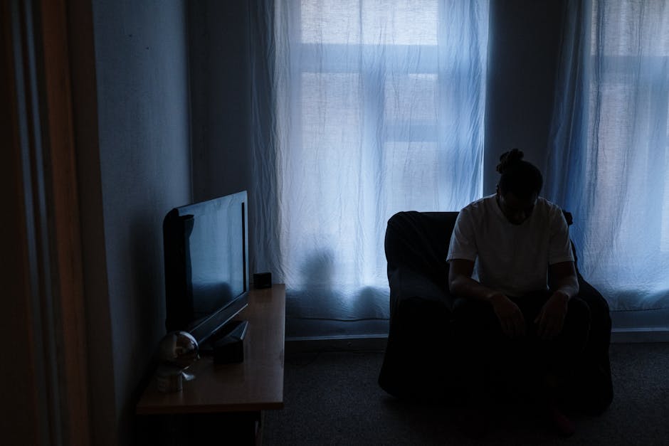 A person sits alone in a dimly lit room, reflecting solitude and moodiness.