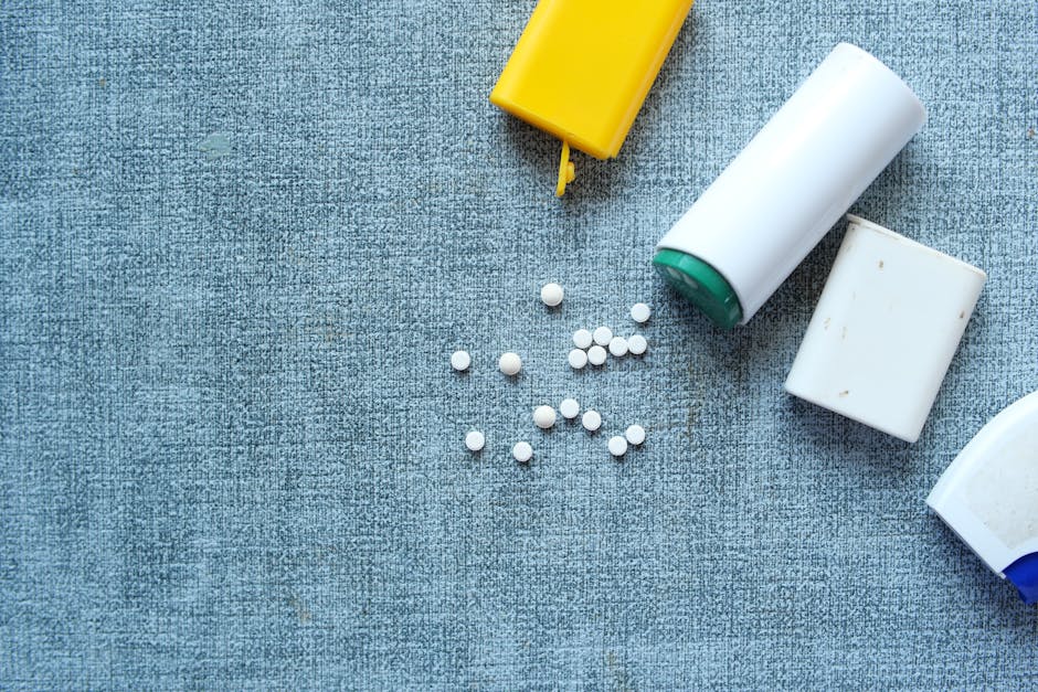Top view of assorted pill containers and medication on a denim-like fabric surface.