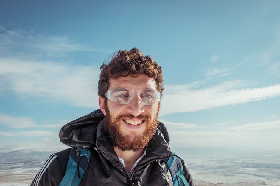 Portrait of a smiling man with a beard and glasses in a winter landscape, enjoying the outdoors.
