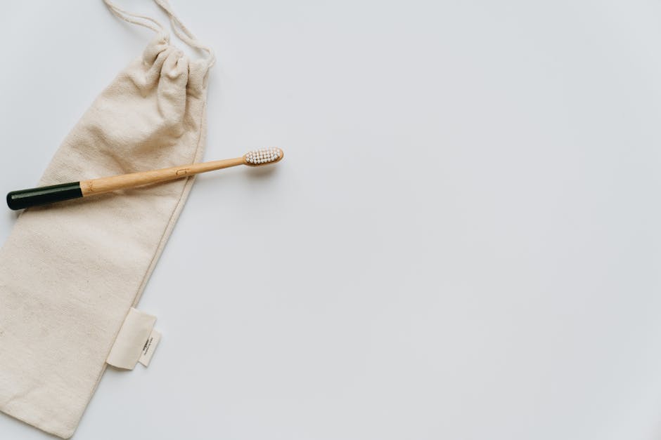 Top view of beige fabric crumpled bag with ties and clean wooden toothbrush on white background with smooth surface