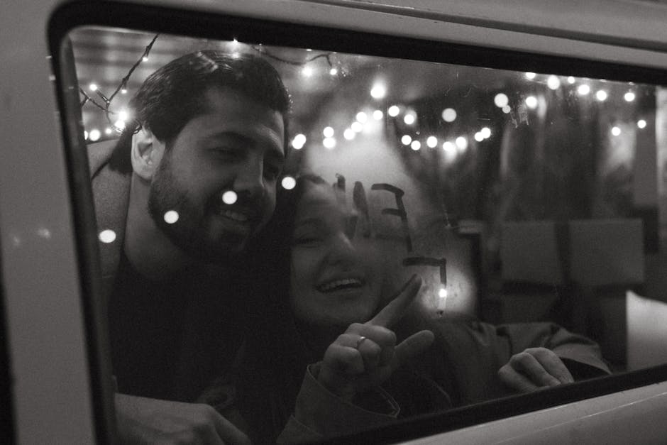 A joyful couple enjoying a winter night inside a vehicle, with twinkling lights creating a festive ambiance.
