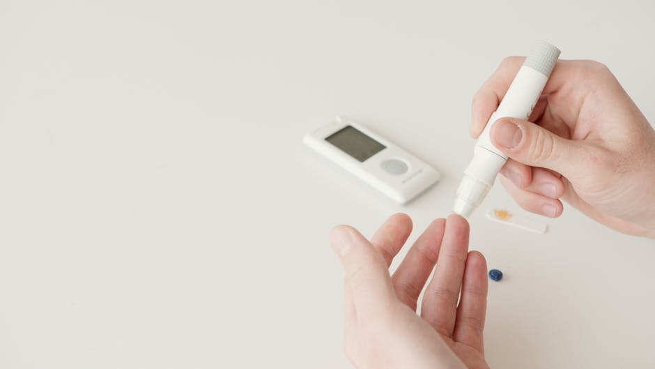 Close-up of hands using a lancet pen and glucometer for blood sugar testing.