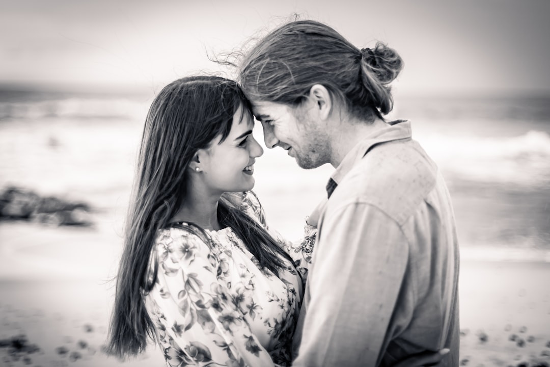 a man and woman standing next to each other on a beach