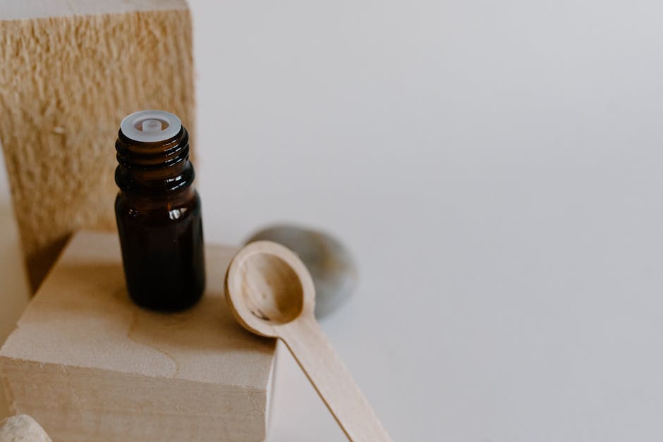 An elegant minimalist composition showcasing an essential oil bottle with a wooden spoon on a wooden block.