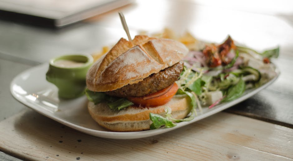 Delicious gourmet burger served with a side of fresh salad and dressing, perfect for a tasty meal.