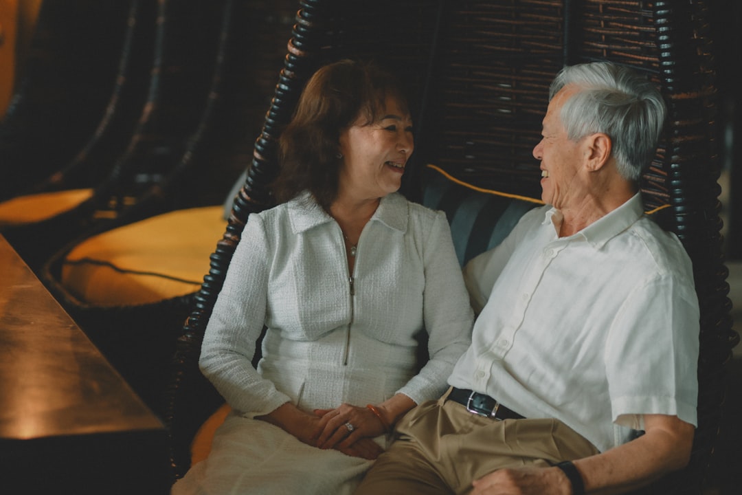 Elderly couple holding hands and smiling at each other.