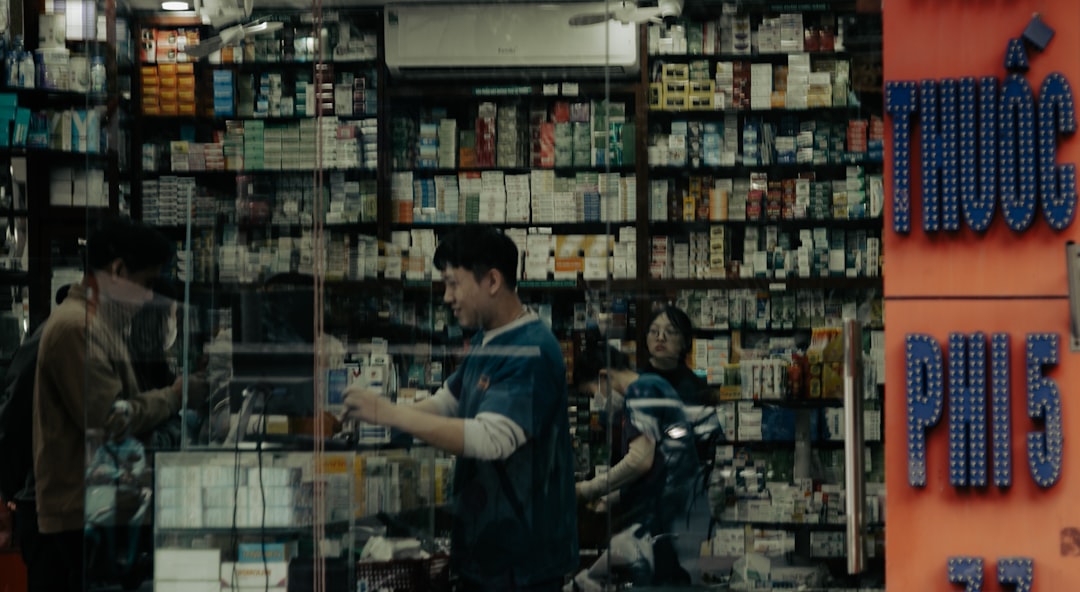 People inside a well-stocked pharmacy with glass doors.