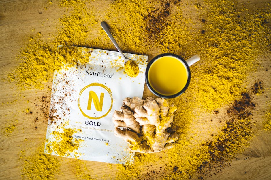 A flat lay of ginger tea with NutriFoodz blend powder, spoon, and ginger root.
