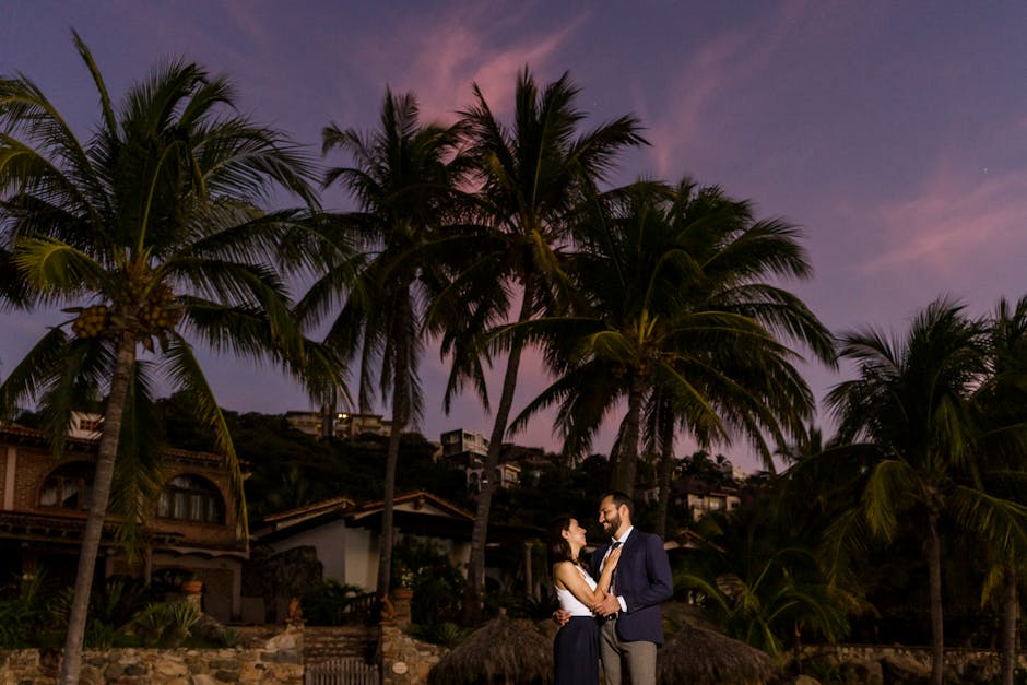 Couple enjoying a romantic moment under palm trees during a vibrant sunset inspiring love and tranquility.