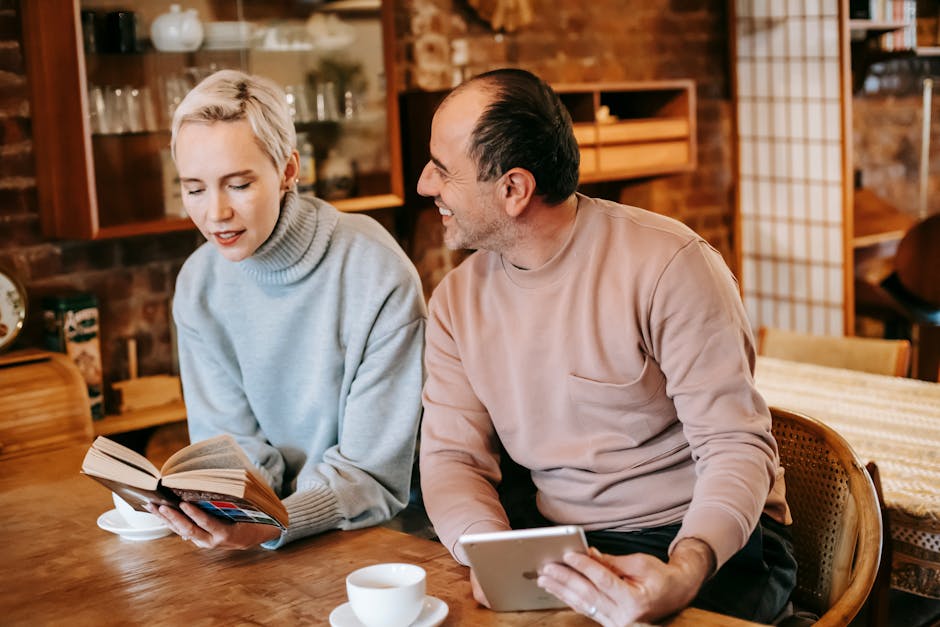 A couple enjoys leisure time indoors, reading and browsing with coffee.