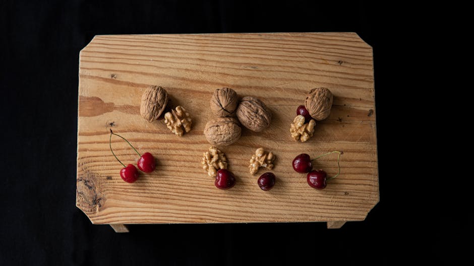 From above of crispy walnuts near sweet cherries on wooden table on black background
