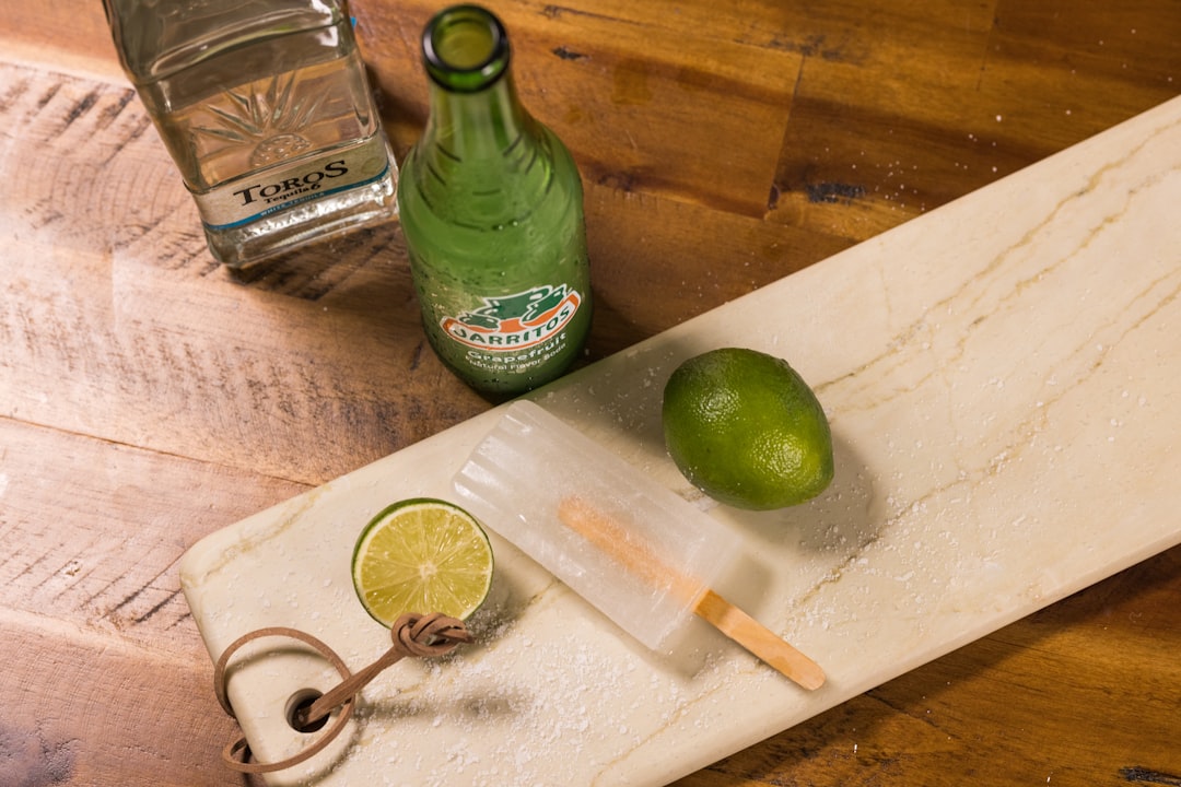 green glass bottle beside white plastic spoon