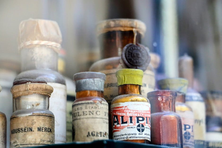 A collection of vintage pharmaceutical bottles displayed in an antique glass cabinet.