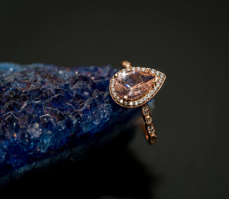 Close-up of a luxurious gold ring with a tear-shaped gemstone on a vibrant blue geode.