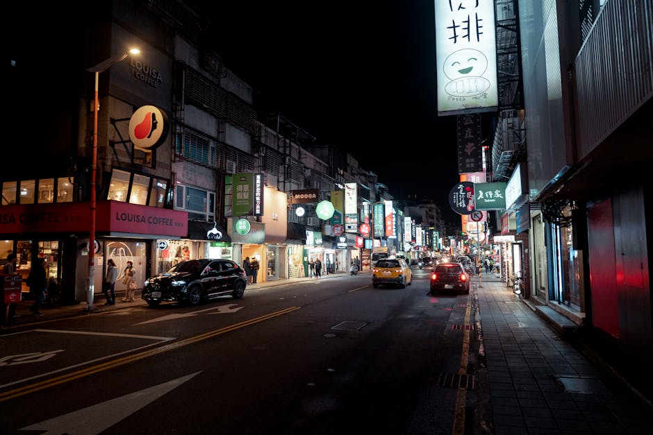 Bustling night street in Taipei with bright city lights and urban activity.