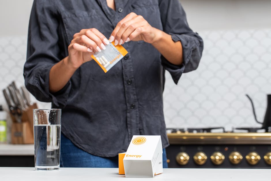 Close-up of a person opening an energy supplement packet in a kitchen setting.
