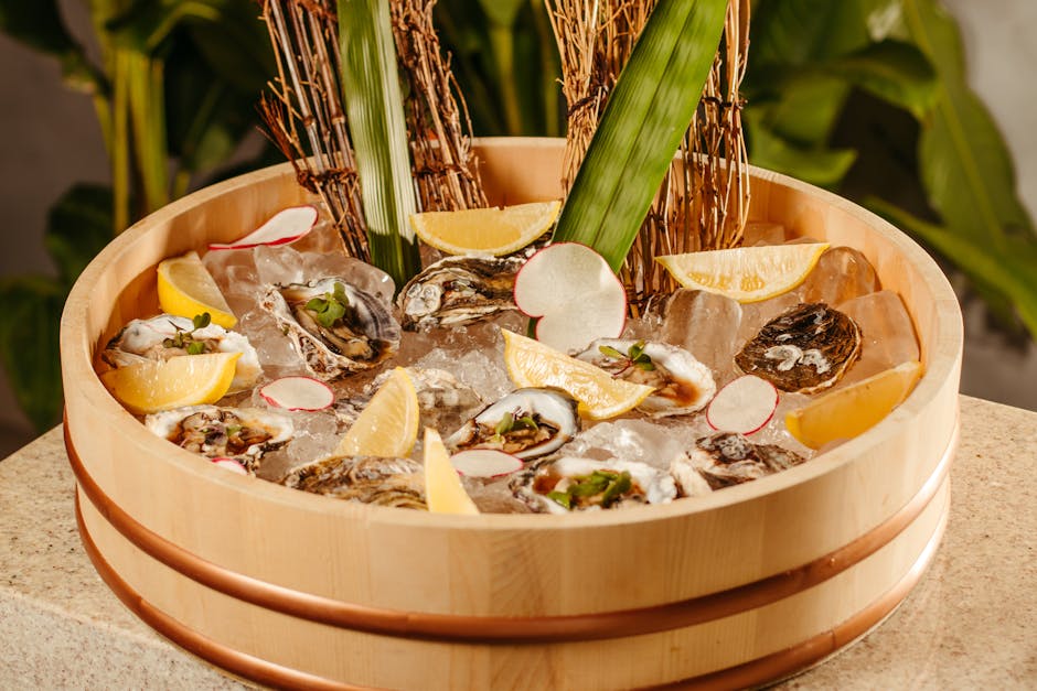 A wooden platter filled with fresh oysters, lemon wedges, and garnishes atop ice.