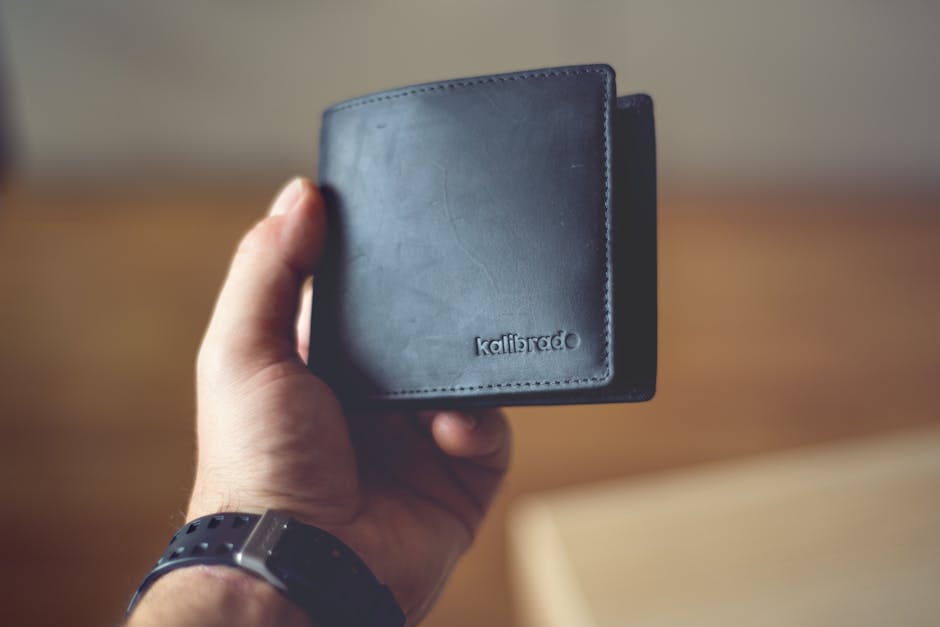 Close-up of a stylish black leather wallet held by a person, showcasing design.