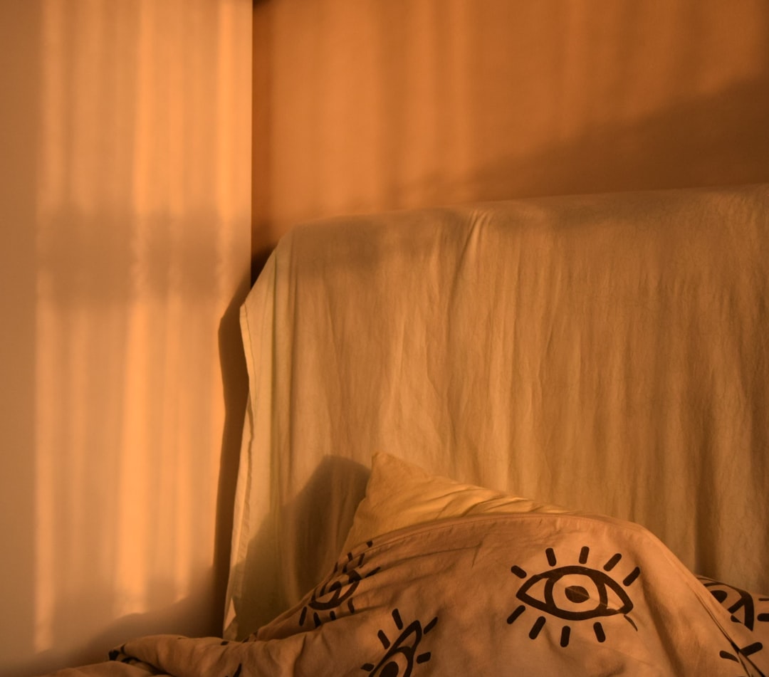 Bed with patterned duvet and shadows on a wall.